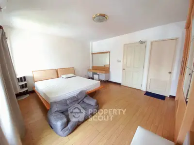 Spacious bedroom with wooden flooring and modern furniture
