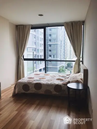 Modern bedroom with large window and city view in high-rise apartment