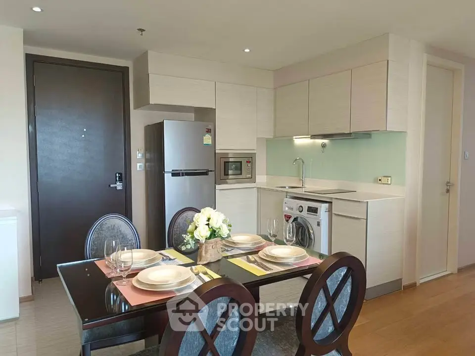 Modern kitchen with dining area, featuring sleek appliances and elegant table setting.