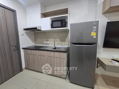 Modern kitchen with sleek cabinetry, stainless steel fridge, and built-in microwave in a compact layout.