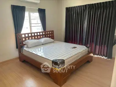 Spacious bedroom with wooden bed frame and large windows for natural light.