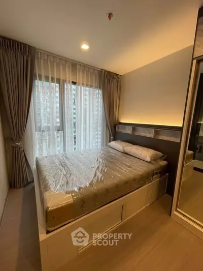 Modern bedroom with large window and stylish decor in a high-rise apartment.