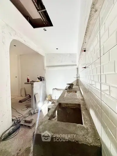 Under-construction kitchen with modern white subway tiles and concrete countertops.