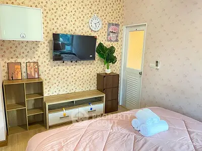 Charming bedroom with floral wallpaper, cozy bed, and modern TV setup.