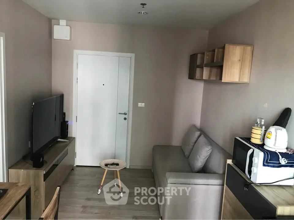 Cozy modern living room with TV, sofa, and stylish decor in compact apartment.