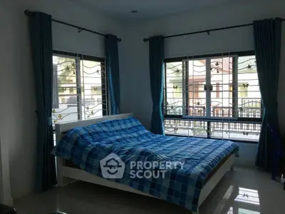 Spacious bedroom with large windows and blue curtains, offering ample natural light and a cozy atmosphere.