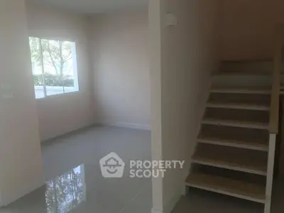 Spacious interior with modern staircase and large window, perfect for natural light.