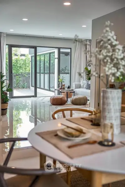 Spacious open-plan living room with elegant decor and large glass doors leading to a lush garden.
