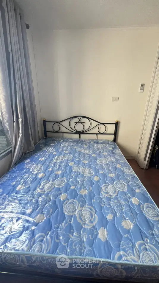 Cozy bedroom with a metal bed frame and floral-patterned mattress, perfect for a restful night's sleep.