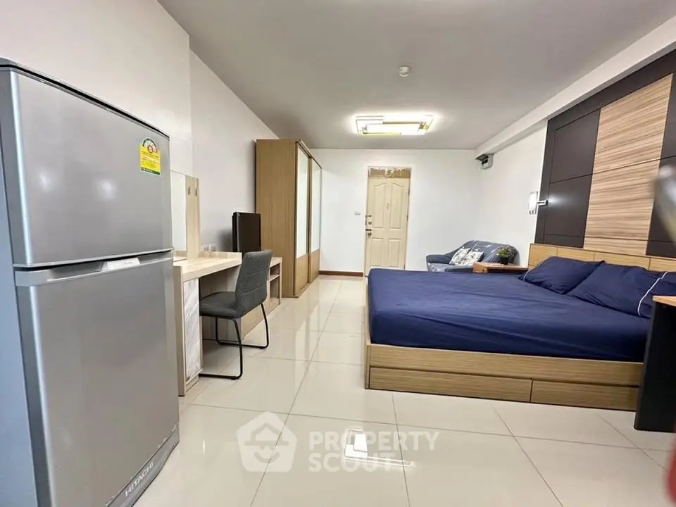Spacious modern studio apartment with sleek furnishings and a large fridge, perfect for urban living.