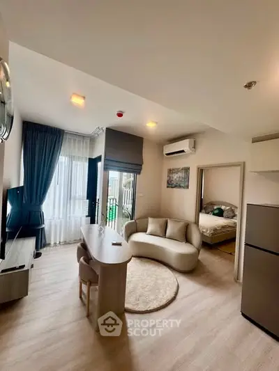 Modern open-plan living room with stylish furniture and natural light, featuring a cozy bedroom view.