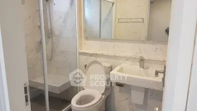 Modern bathroom with marble walls and glass shower enclosure