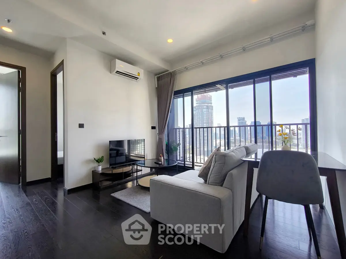 Modern living room with city view and sleek furnishings in high-rise apartment.