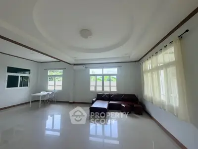 Spacious living room with modern design and ample natural light, featuring a cozy sectional sofa and elegant ceiling.