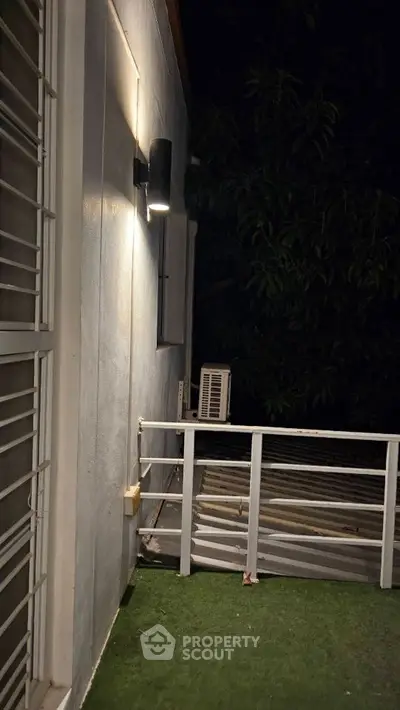 Charming balcony with night lighting and lush greenery view, perfect for relaxation.