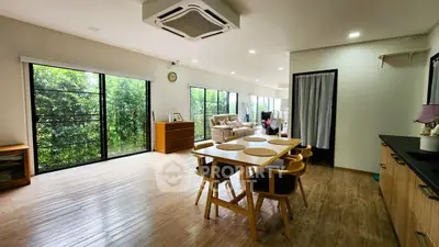 Spacious open-plan living and dining area with large windows and wooden flooring.