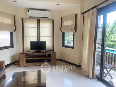 Charming living room with pool view and natural light, featuring cozy furniture and modern decor.