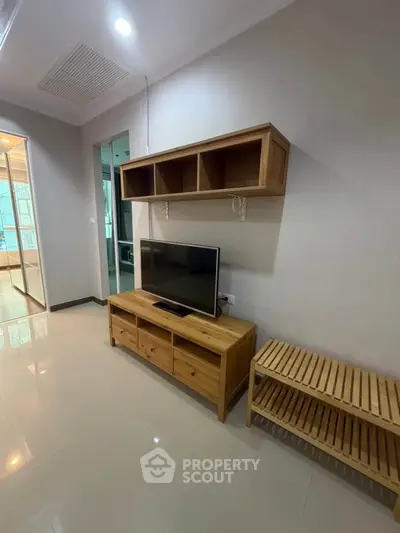 Modern living room with wooden TV stand and shelving, sleek design, bright lighting, and tiled flooring.