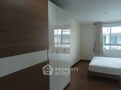 Spacious bedroom with modern wardrobe and large window offering natural light.