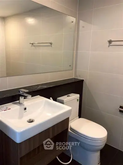 Modern bathroom with sleek fixtures and large mirror in contemporary apartment.