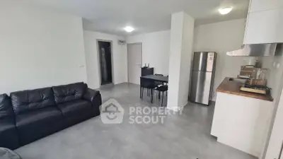 Modern open-plan living room with sleek kitchen and dining area, featuring contemporary furniture and appliances.