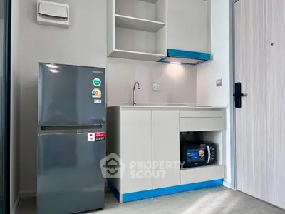 Modern compact kitchen with fridge and microwave in a stylish apartment