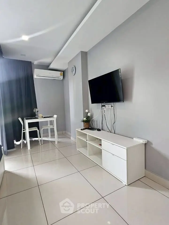 Modern living room with sleek TV setup and dining area, featuring minimalist design and bright ambiance.