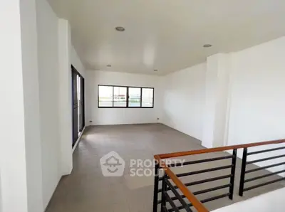 Spacious open-plan living area with large windows and modern railing, perfect for natural light and contemporary living.