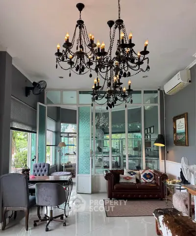 Elegant living room with chandelier, leather sofa, and large windows for natural light.