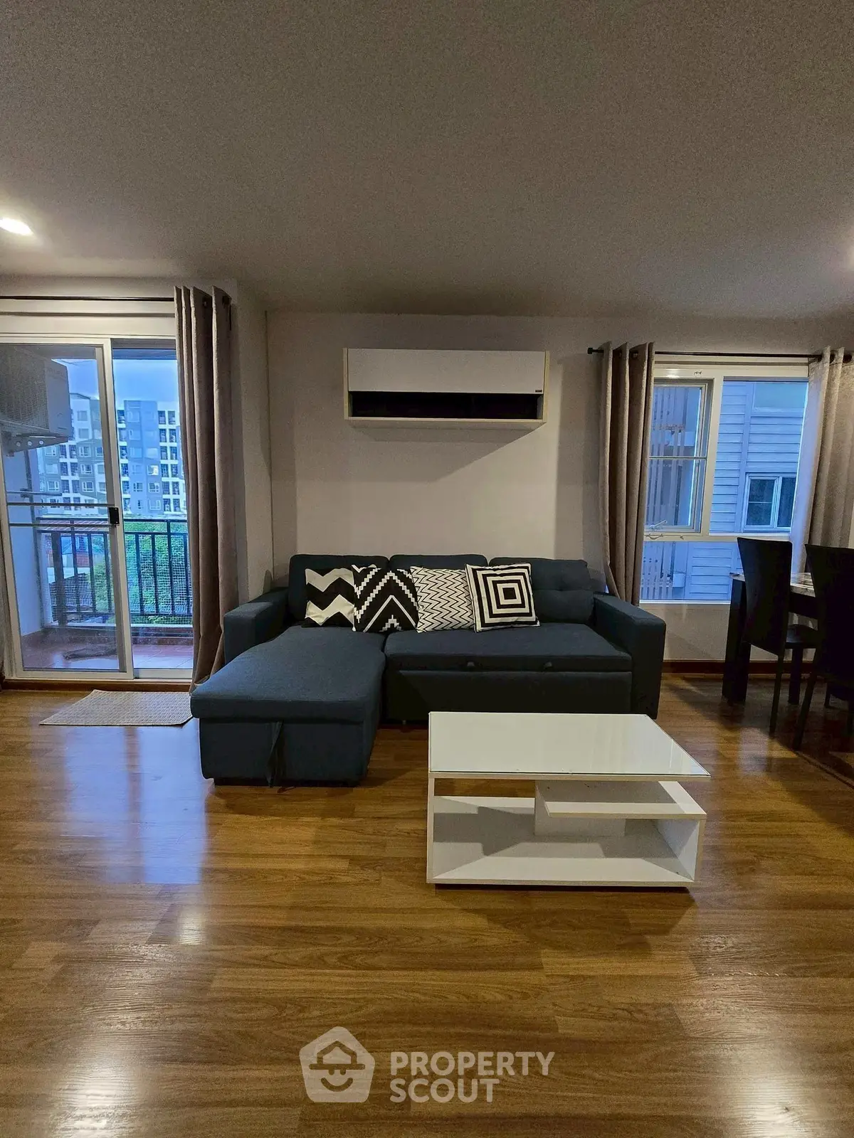Spacious living room with modern sofa and balcony view in urban apartment.