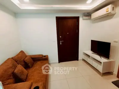 Cozy living room with modern sofa and TV setup, featuring air conditioning and sleek design.