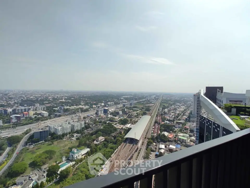 Stunning cityscape view from high-rise balcony overlooking urban skyline and railway.