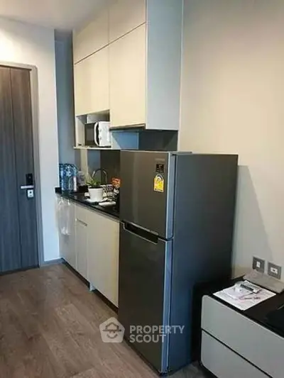 Modern kitchen with sleek cabinetry and stainless steel fridge in a compact layout.