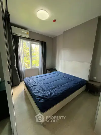 Modern bedroom with large window and stylish decor in a cozy apartment.