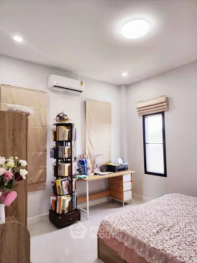 Cozy bedroom with modern decor, featuring a study desk and air conditioning.