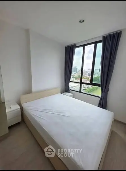 Bright bedroom with large window offering city views and modern furnishings.