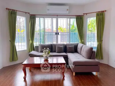 Charming living room with large windows, cozy sectional sofa, and elegant wooden coffee table, perfect for relaxation.