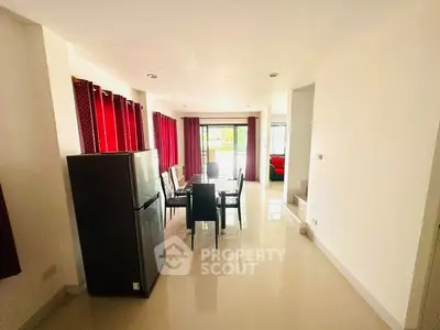 Spacious dining area with modern fridge and large windows for natural light.