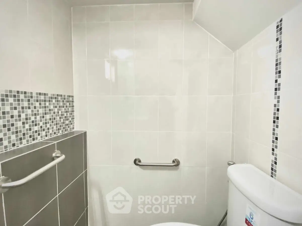 Modern bathroom with sleek tiles and safety handrail