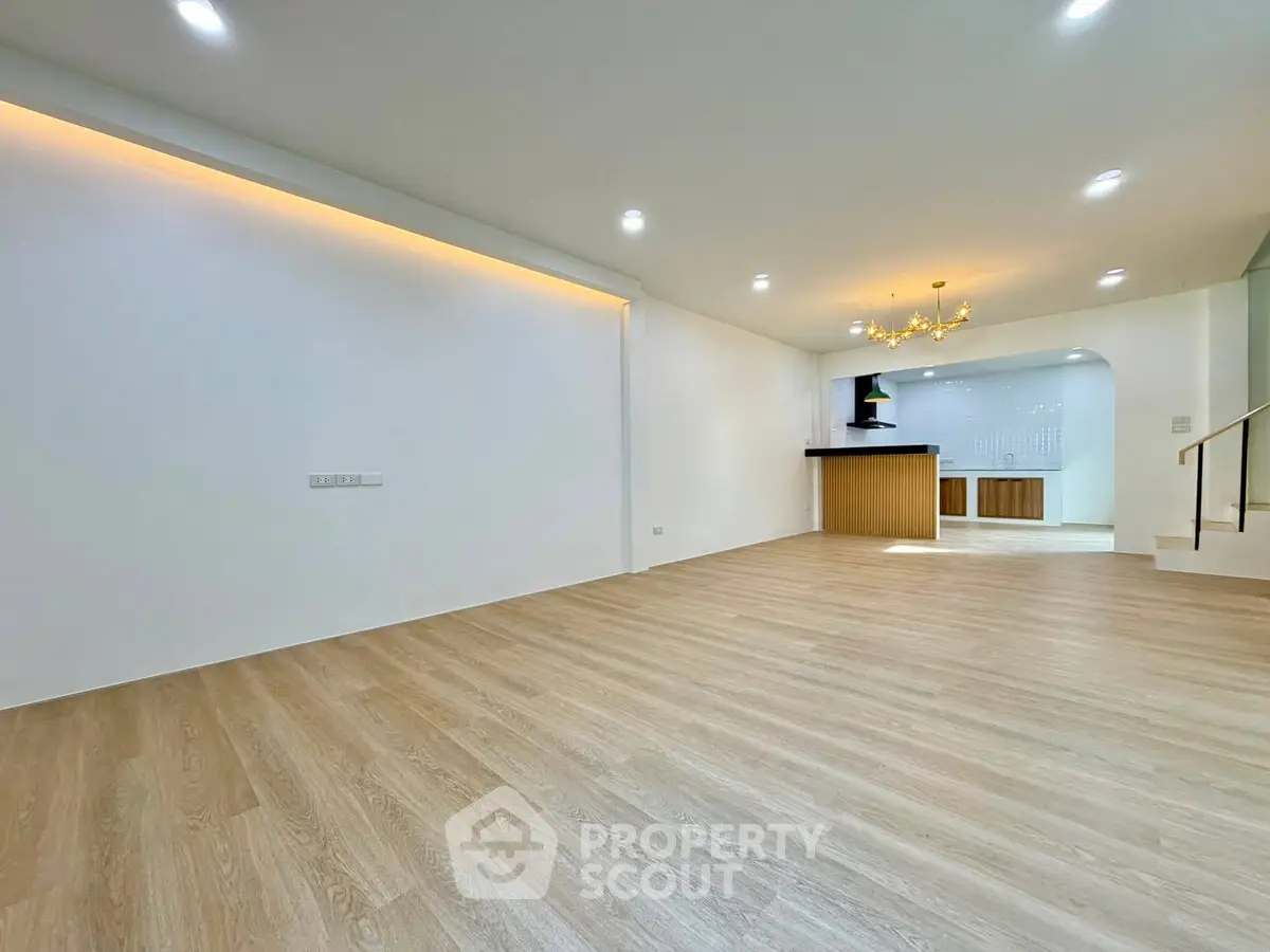 Spacious open-plan living area with modern kitchen and elegant lighting.
