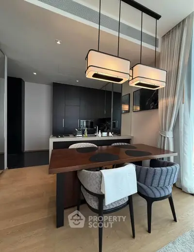 Modern dining area with elegant lighting and sleek kitchen design in luxury apartment.