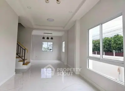 Spacious modern living room with large windows and elegant staircase in a bright, airy home.