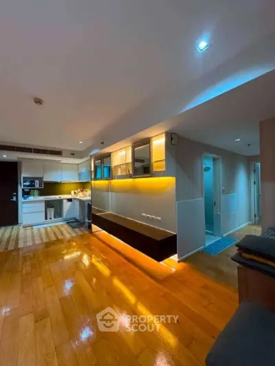 Modern living room with wooden flooring and ambient lighting in a stylish apartment.
