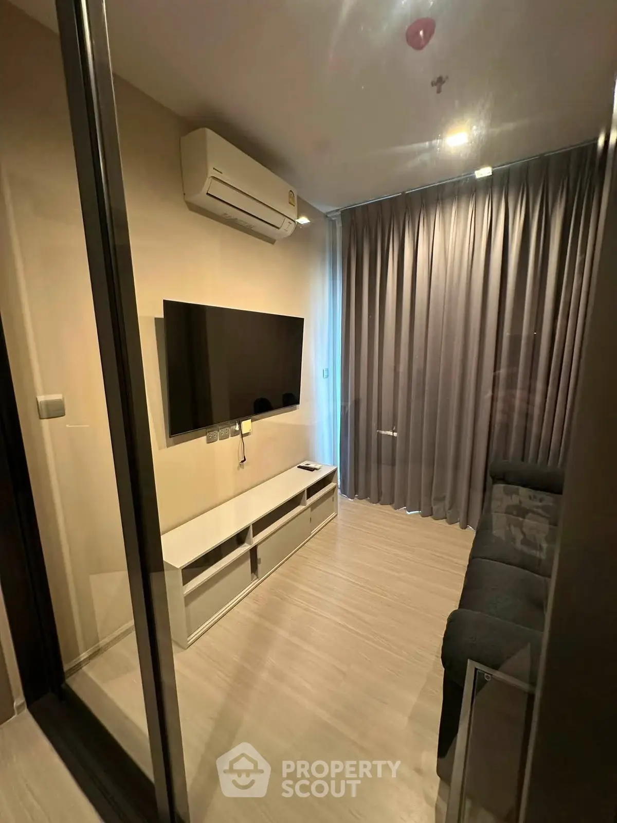 Modern living room with sleek design, featuring a wall-mounted TV and air conditioning, perfect for cozy relaxation.