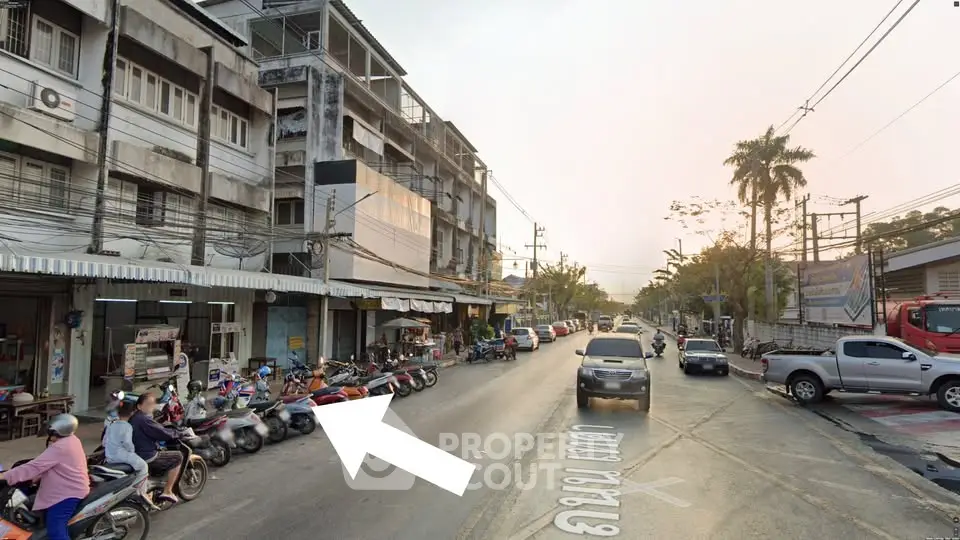 Street view of urban area with residential buildings and parked scooters, showcasing vibrant city life.