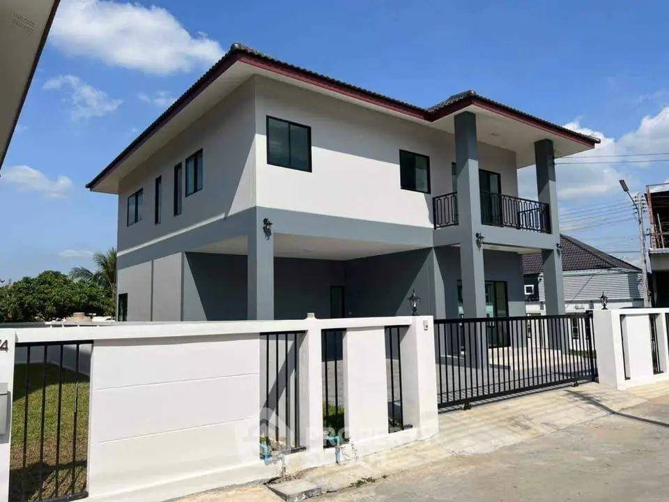 Modern two-story house with spacious balcony and gated driveway in sunny suburban neighborhood.
