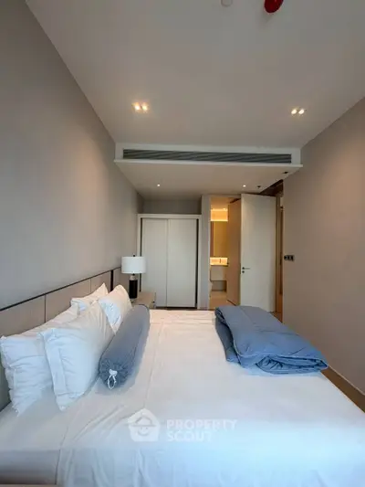 Modern bedroom with stylish decor and ensuite bathroom in luxury apartment.