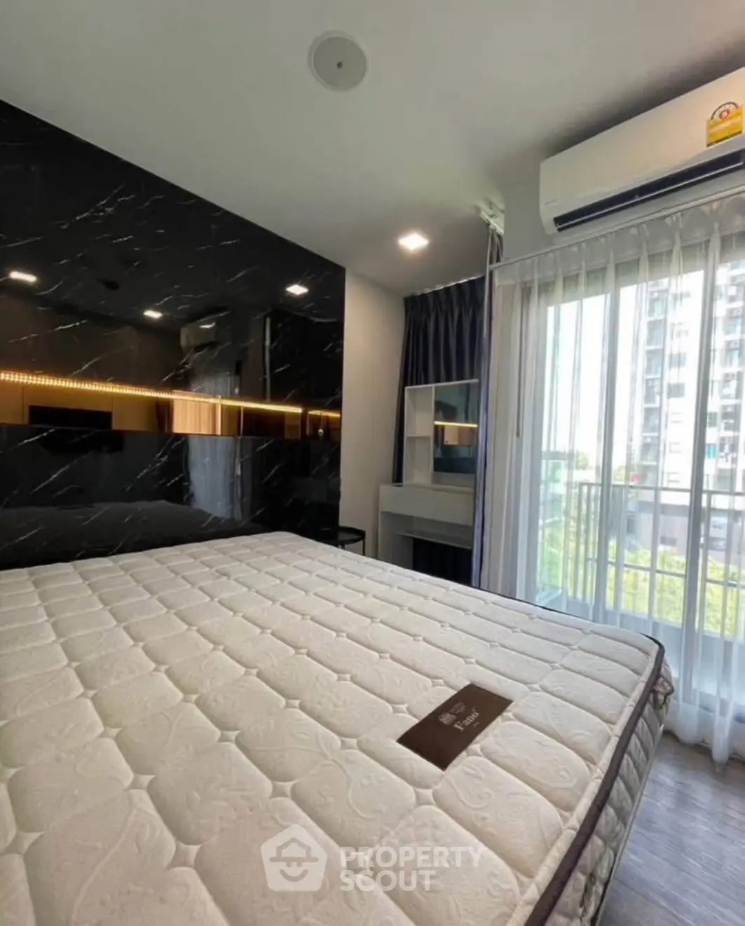 Modern bedroom with large window and stylish decor in a high-rise apartment.