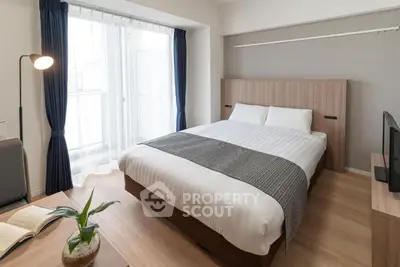 Modern bedroom with cozy double bed and natural light from large window.