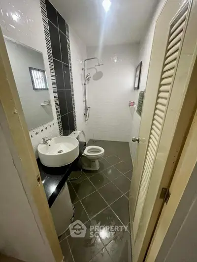 Compact modern bathroom with sleek fixtures, wall-mounted sink, and a well-lit shower area, perfect for urban living.